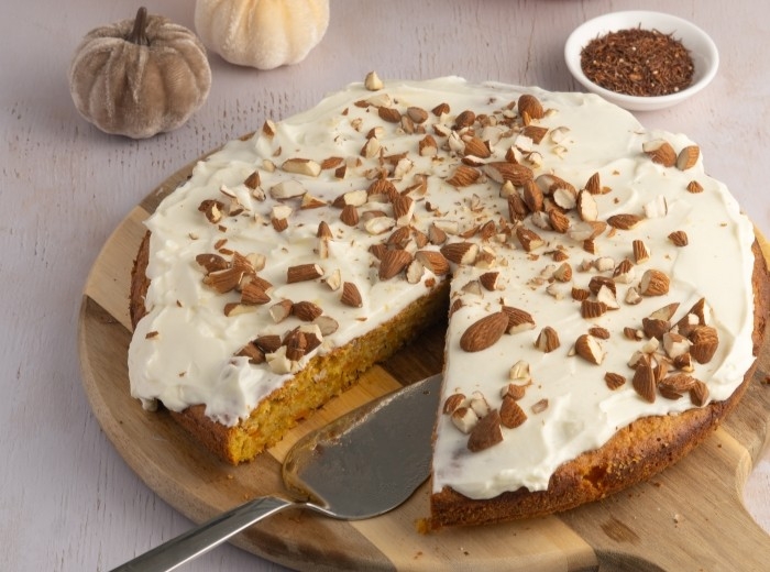 runder rooibos kuerbis apfelkuchen mit mandelstücken auf einem holzbrett